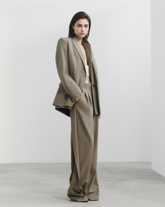Elegant woman in a cream sweater and beige trousers walking in Paris – minimalist neutral tone outfit inspiration